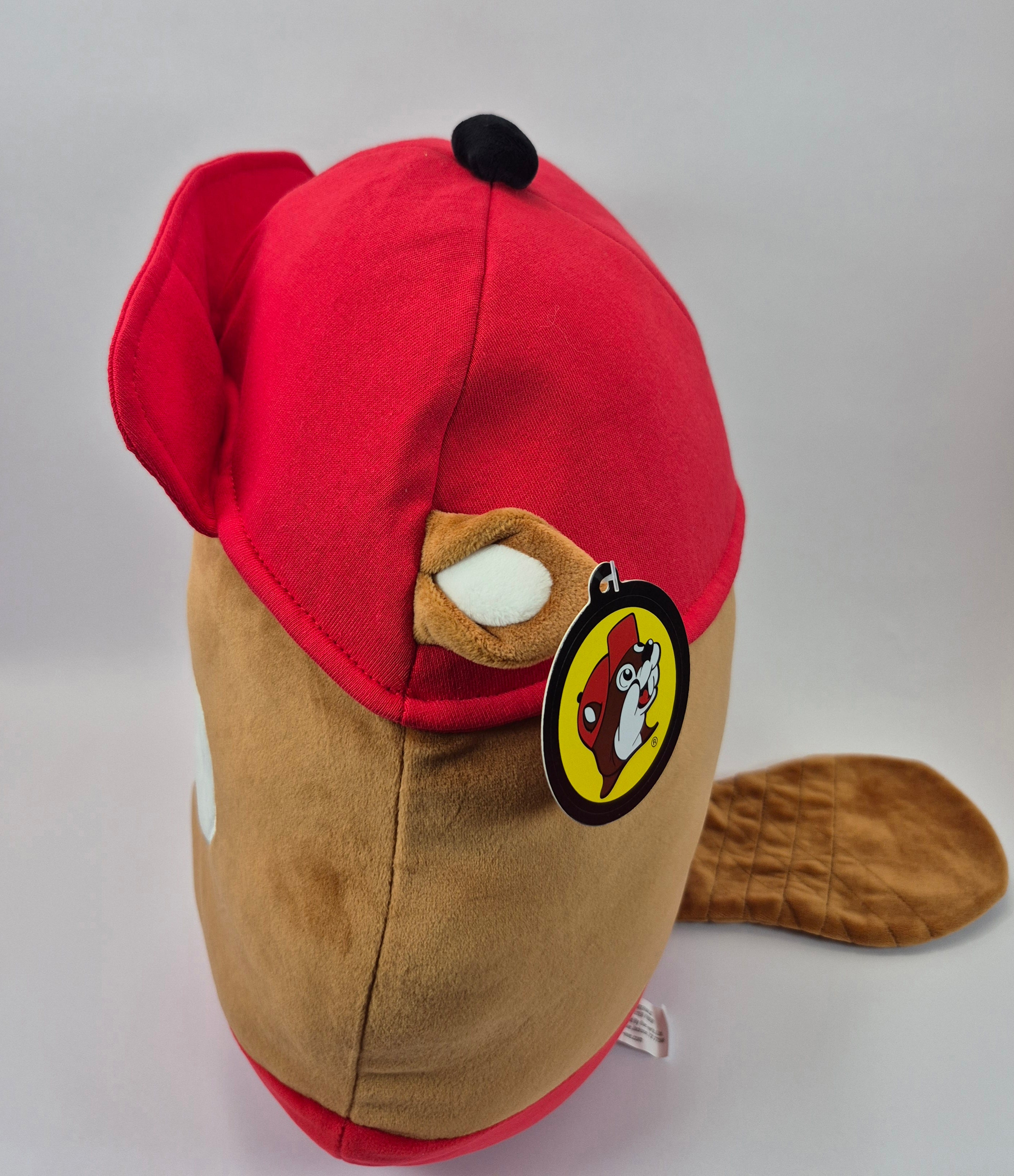 Plush toy resembling a beaver with a red hat and brown body on a white background