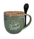 Green mug with 'Texas' design and a black spoon on a white background